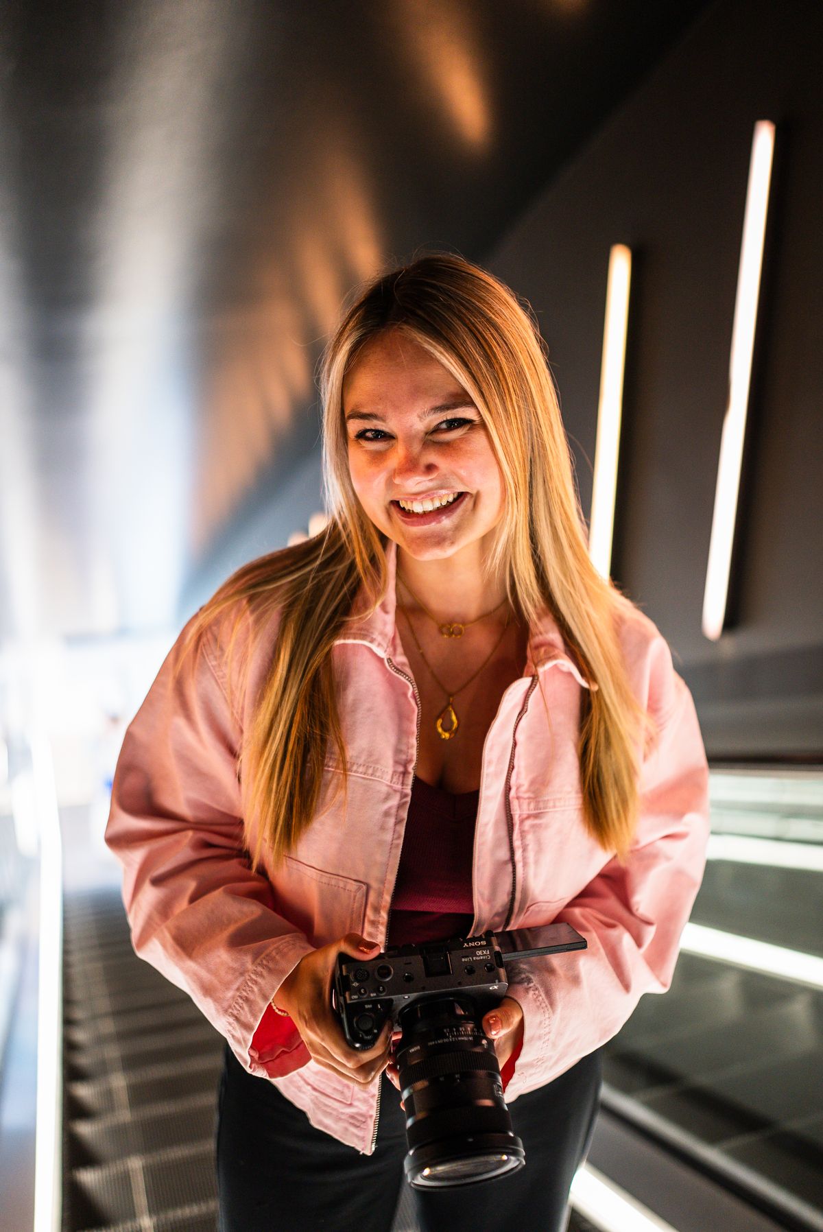 Portret van Martine met haar filmcamera, lachend in de camera.